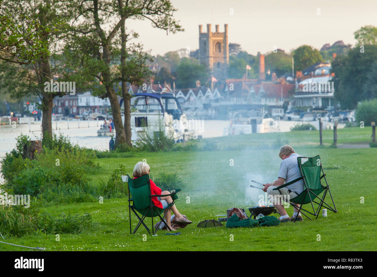 A couple enjoy a peaceful Summer barbecue or barbeque by their boat on ...