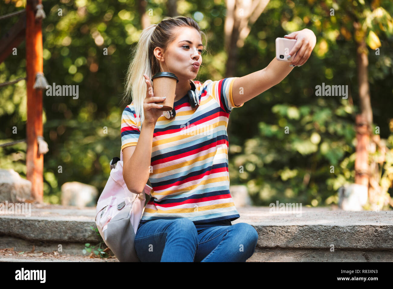 Image of a happy cute young girl take selfie by mobile phone holding ...