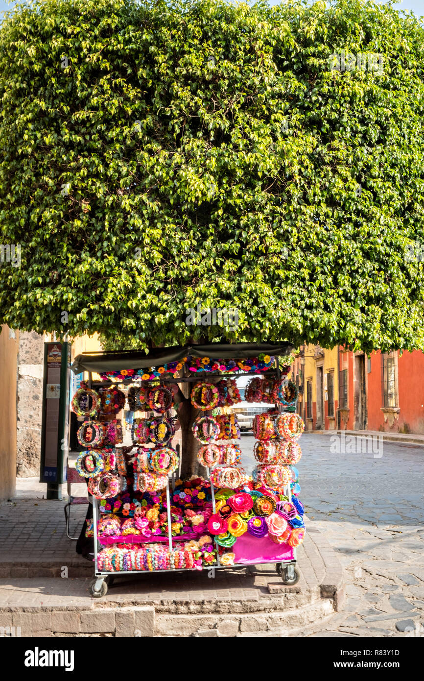 A vendor sells floral crowns made with dried flowers along Ignacio Hernandez Macias Street in the historic district of San Miguel de Allende, Mexico. Stock Photo