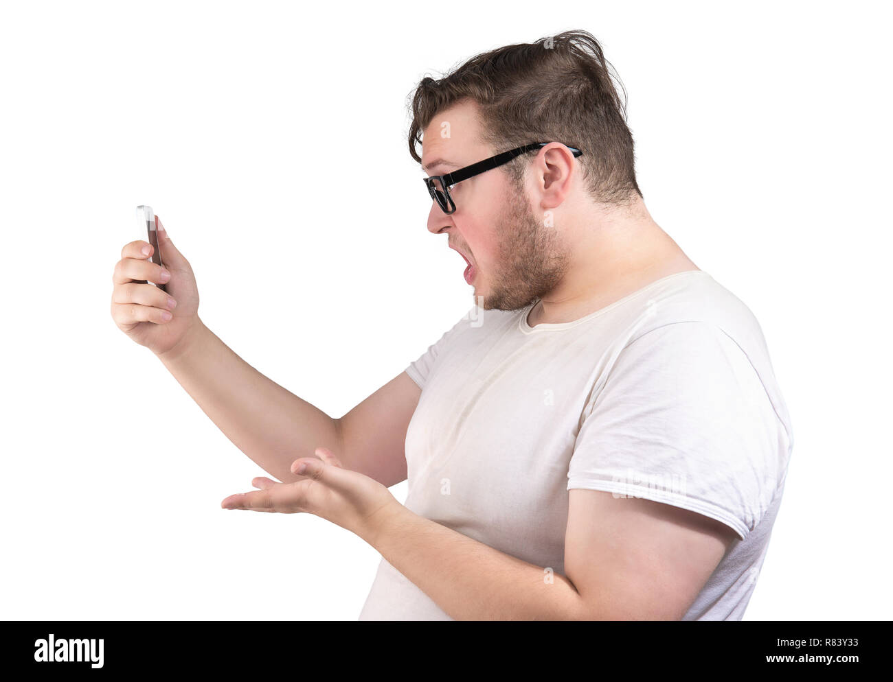 Side view of obese man in glasses speaking via smartphone looking angry and displeased on white background Stock Photo