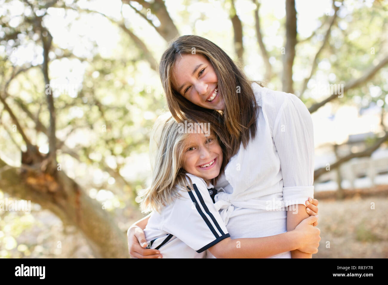 Portrait of two smiling sisters standing with arms around each other ...