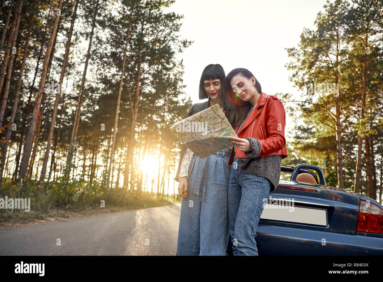 Two women trying to find the way on map near cabriolet Stock Photo