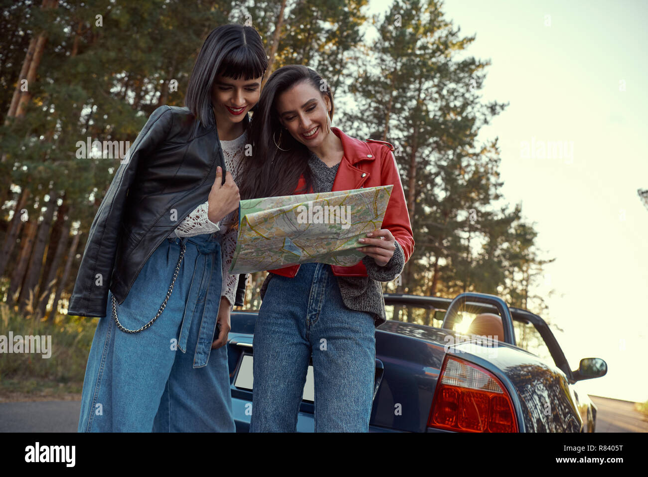 Two women trying to find the way on map near cabriolet Stock Photo