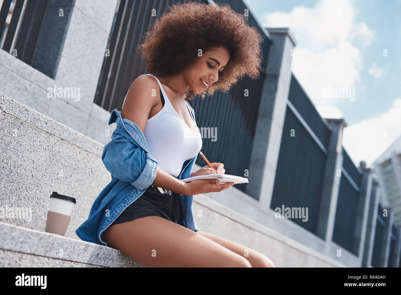 Young woman free style on the street sitting on stairs with cup  Stock Photo