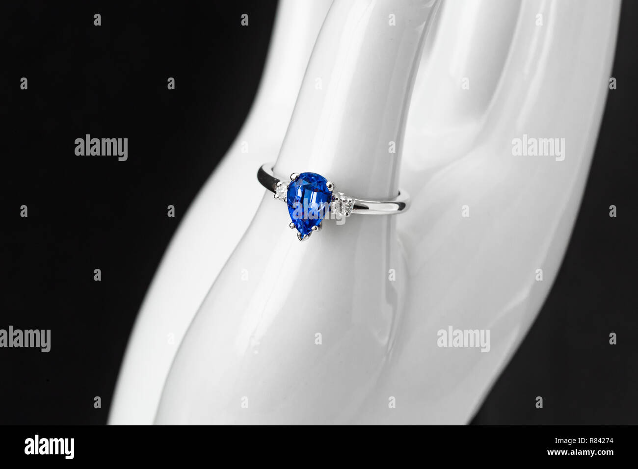 A brilliant blue Sapphire teardrop and Diamond 14 karat white gold ring on display Stock Photo