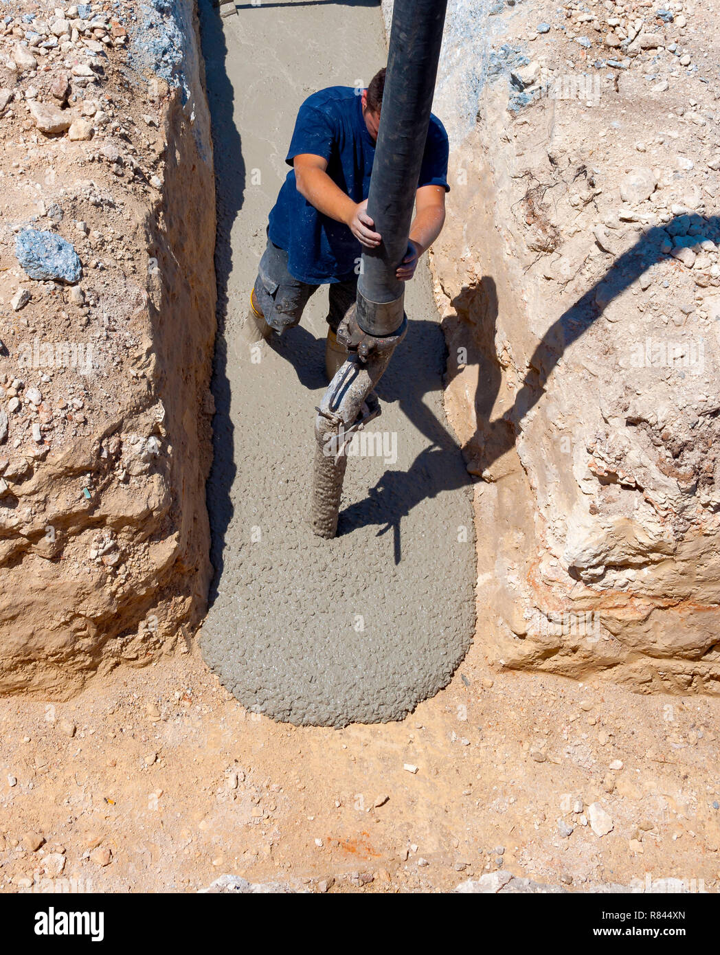 building construction worker pouring cement or concrete with pump tube