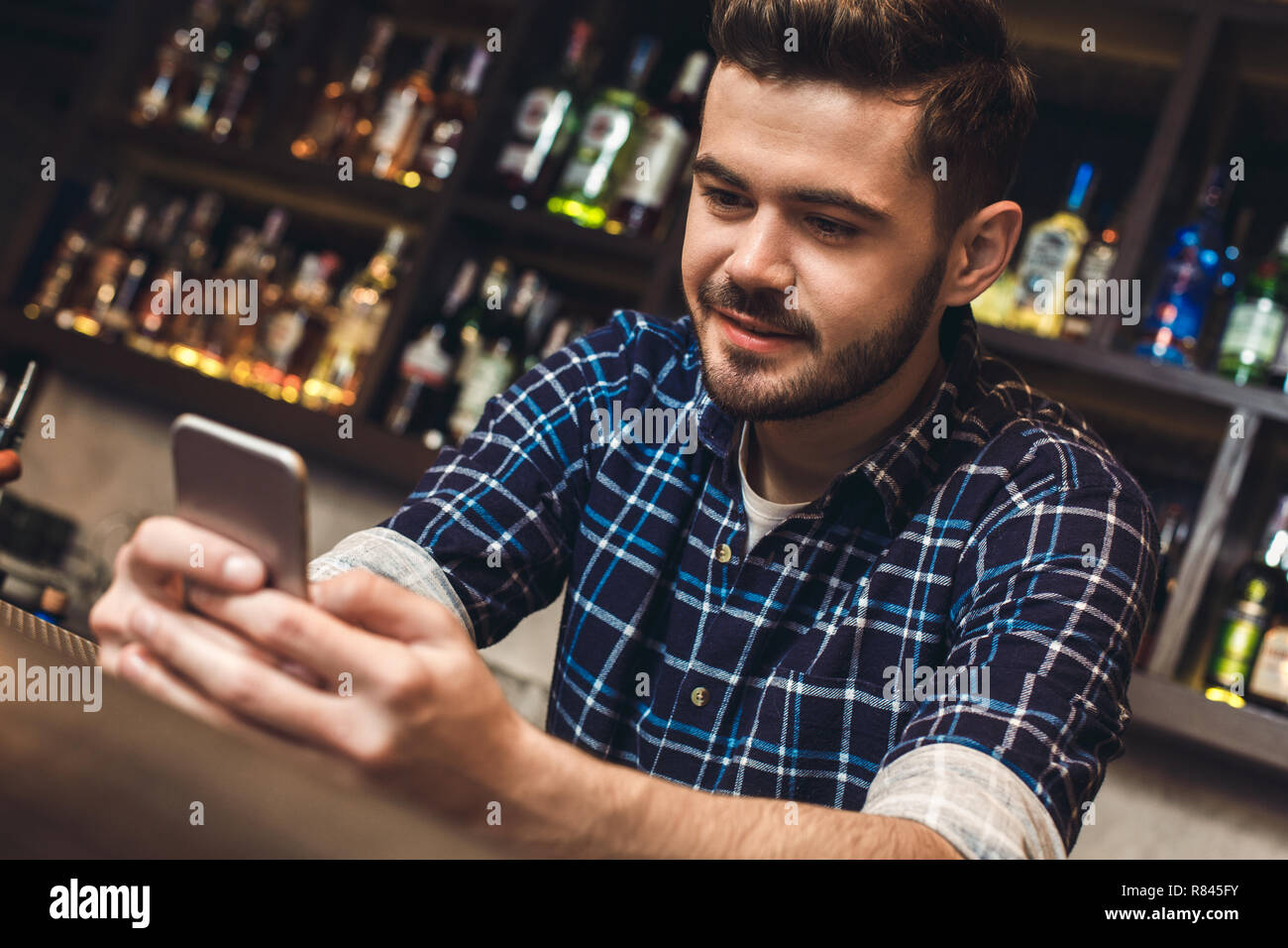 Young bartender leaning on bar counter browsing internet joyful close-up Stock Photo