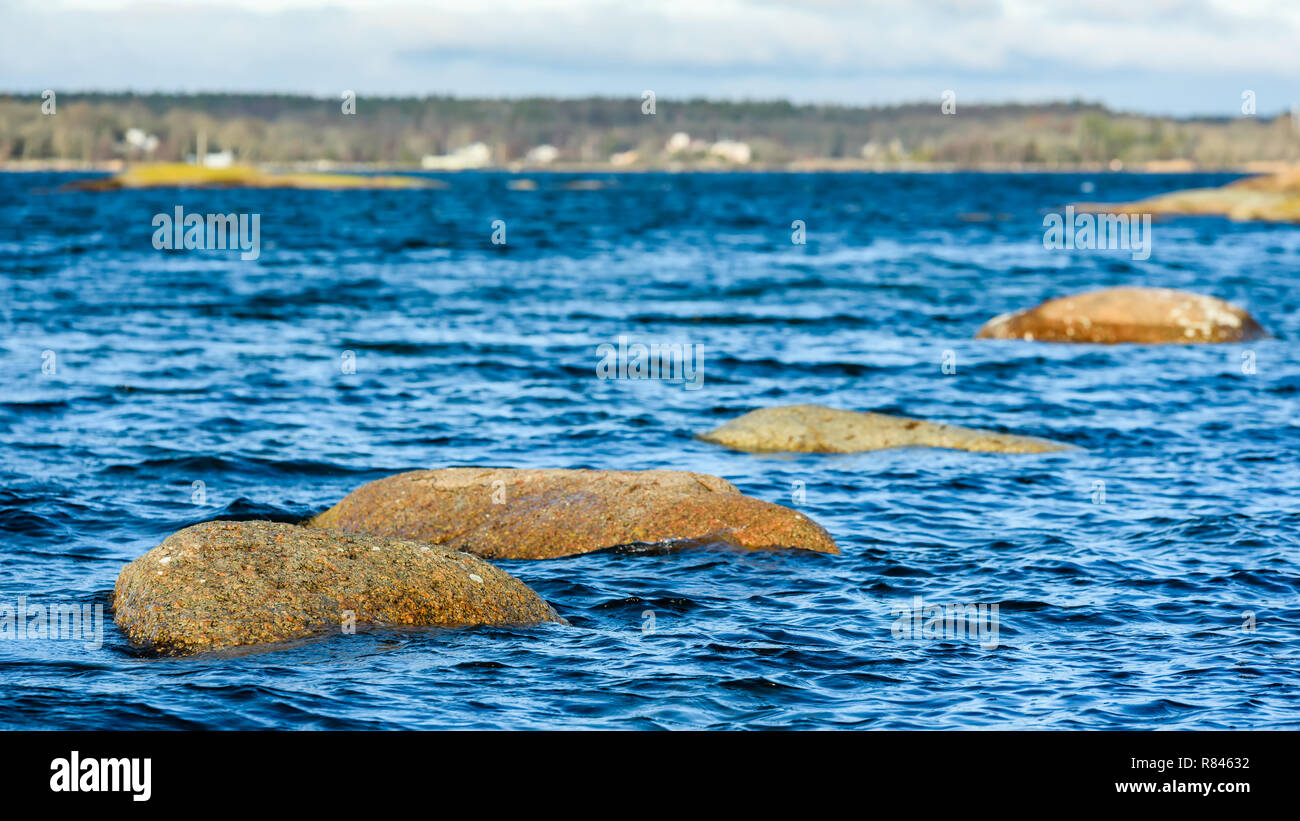 Parts of coastal rocks barely above the sea surface. Shallow focus on frontmost rock and blurred background. Stock Photo