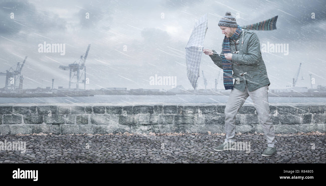 Pedestrian with an umbrella is facing strong wind and rain Stock Photo