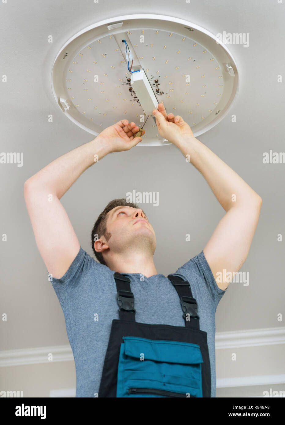Male electrician mounting LED lamp at home Stock Photo - Alamy