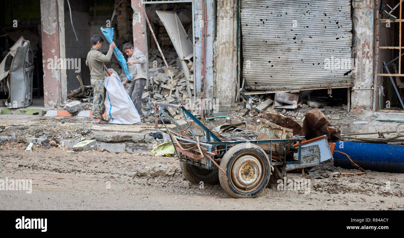 Boys scavenge recyclable metal and plastic from rubble in the old city of Mosul, Iraq. Stock Photo