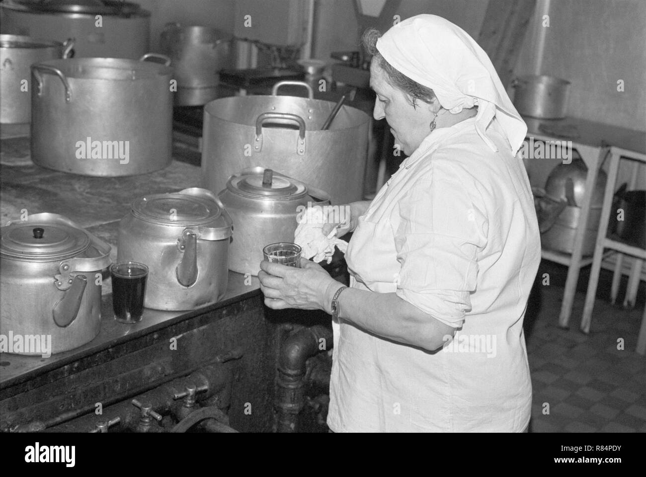 Moscow, USSR - November 23, 1989: Canteen in the Ministry of the Automotive Industry of the USSR. Woman emloyee of the canteen makes tea in large metal tea pot in the cooking area of the canteen. Stock Photo