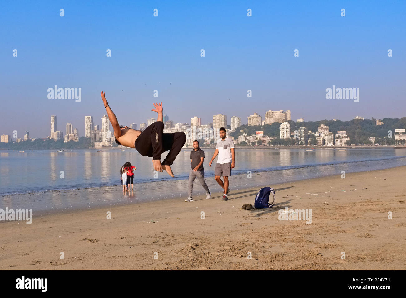 A young man on the beach by the Arabian Sea off Marine Drive, Mumbai, India, practicing somersaults as part of a dance routine Stock Photo