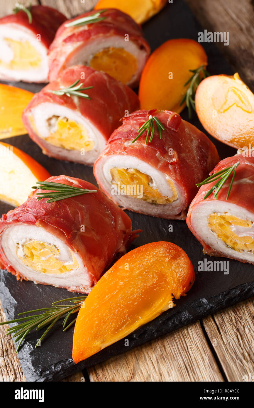 Baked roll pork tenderloin stuffed with persimmon and cheese wrapped in prosciutto closeup on