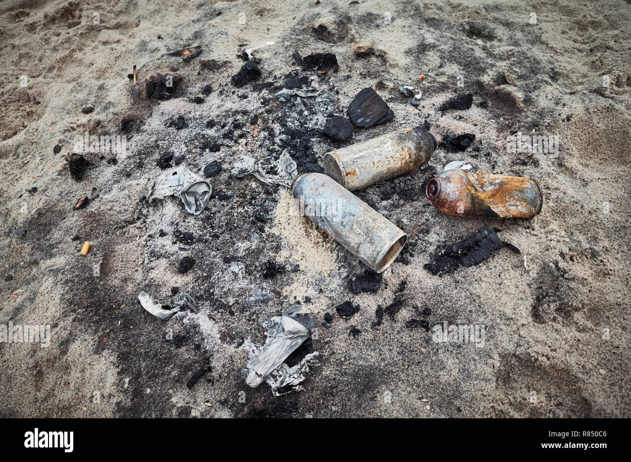 Burnt cans on sand, environmental pollution concept. Stock Photo