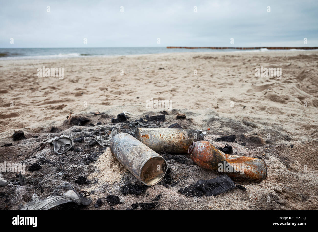 Burnt cans on a beach, environmental pollution concept. Stock Photo