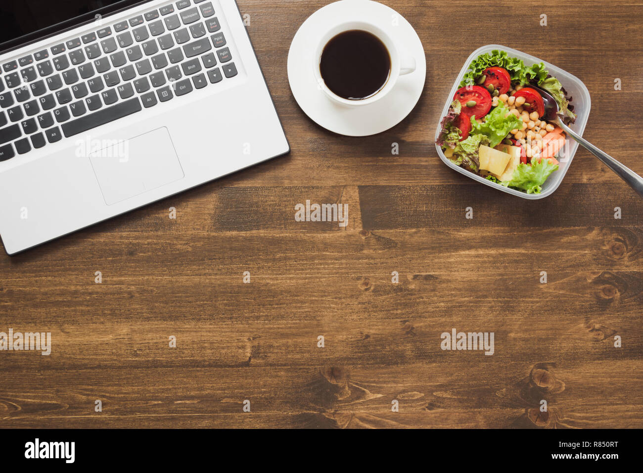 Healthy business lunch in office, salad, coffee on wooden table. Top