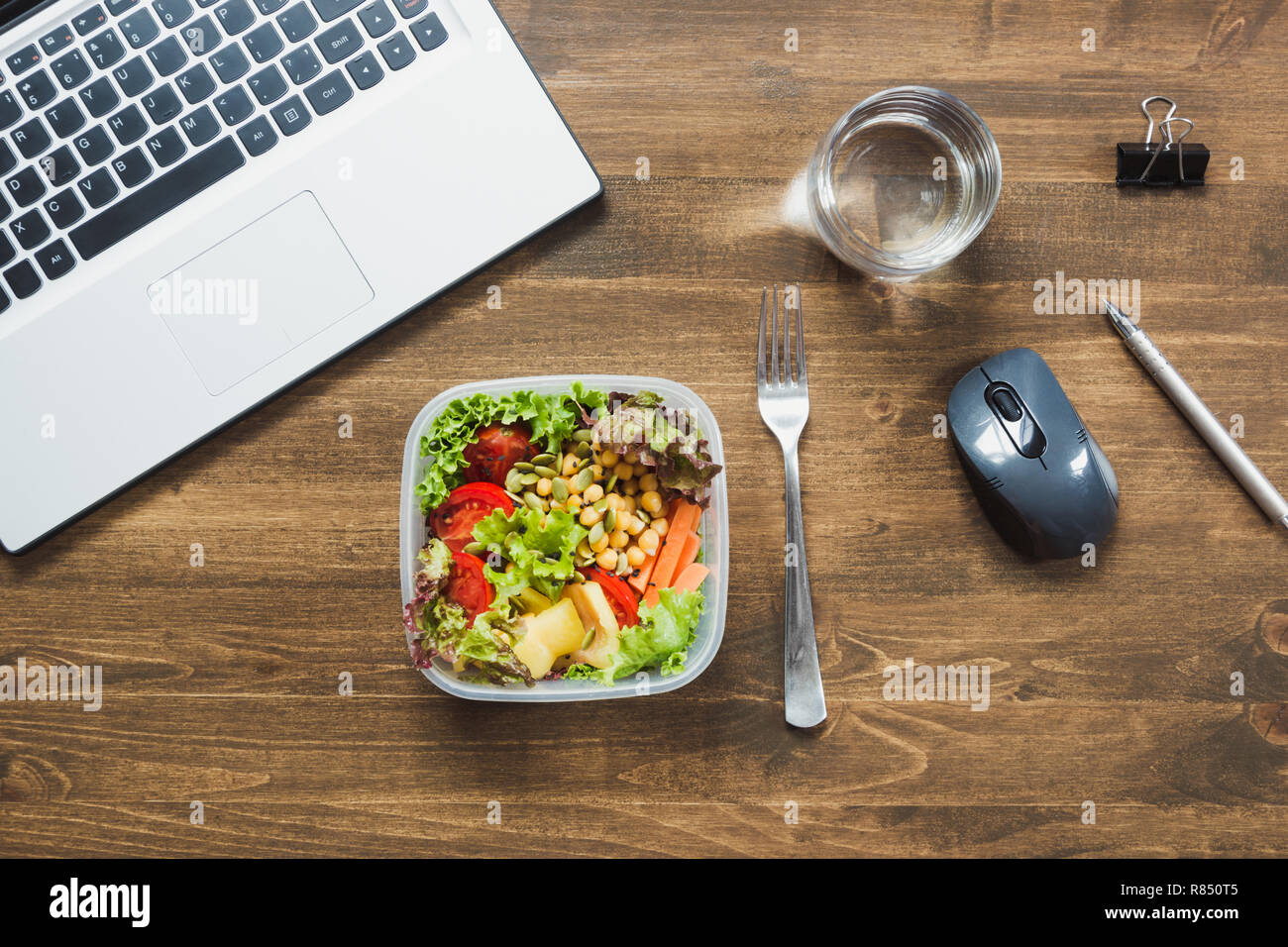 Healthy business lunch in office, salad, water on wooden table. Concept