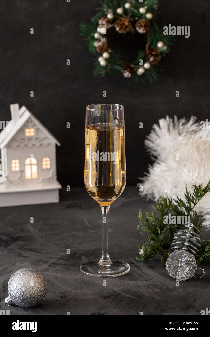 Christmas glass with champagne with white tinsel and christmas toy at black background Stock Photo