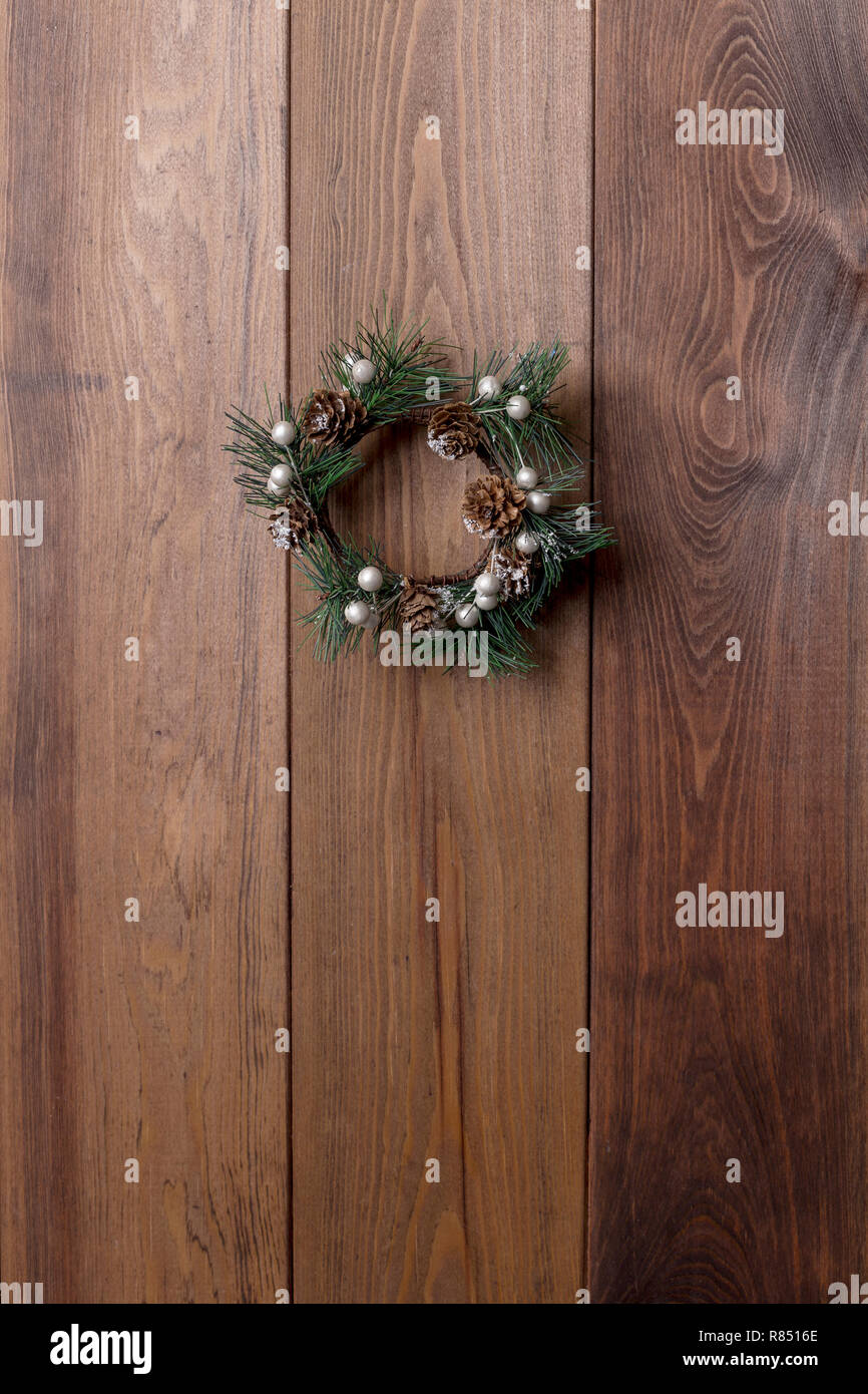 Christmas small green wreath with cones at wood board. Copy space