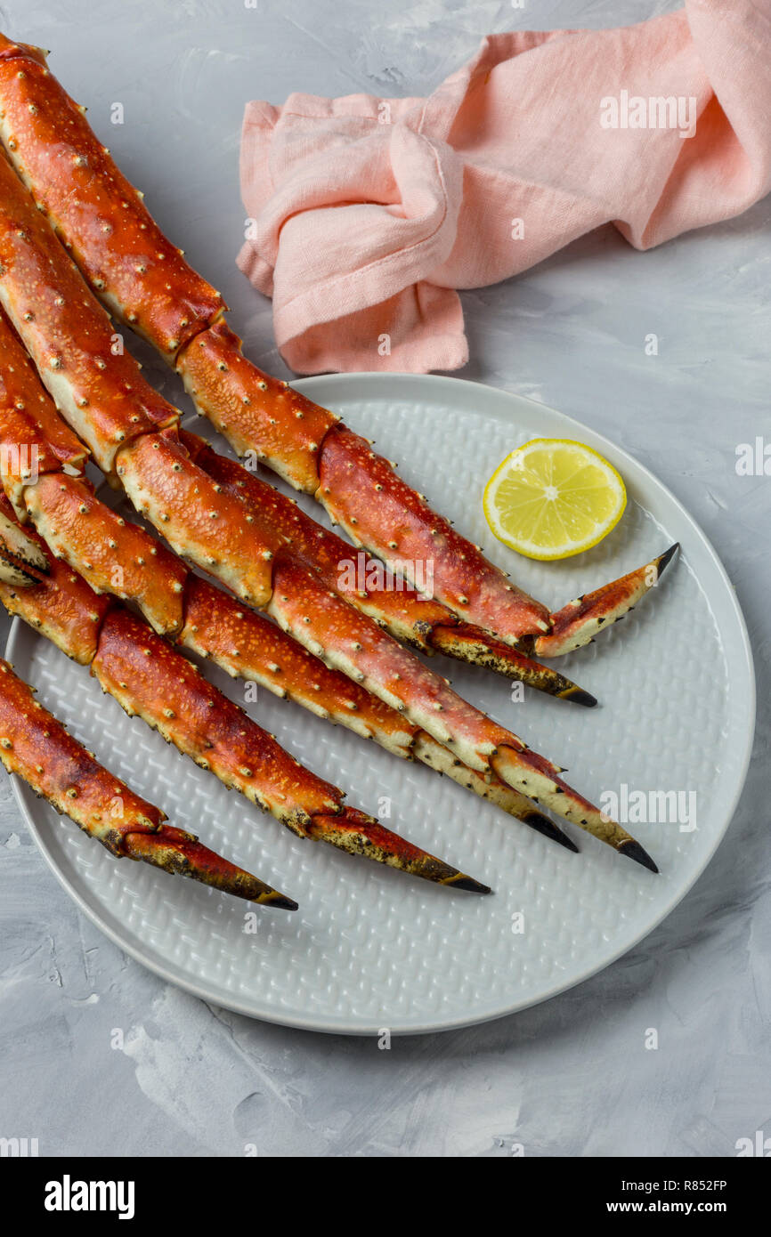 Luxury Kamchatka's Crab claw on gray plate with lemon slice and pink