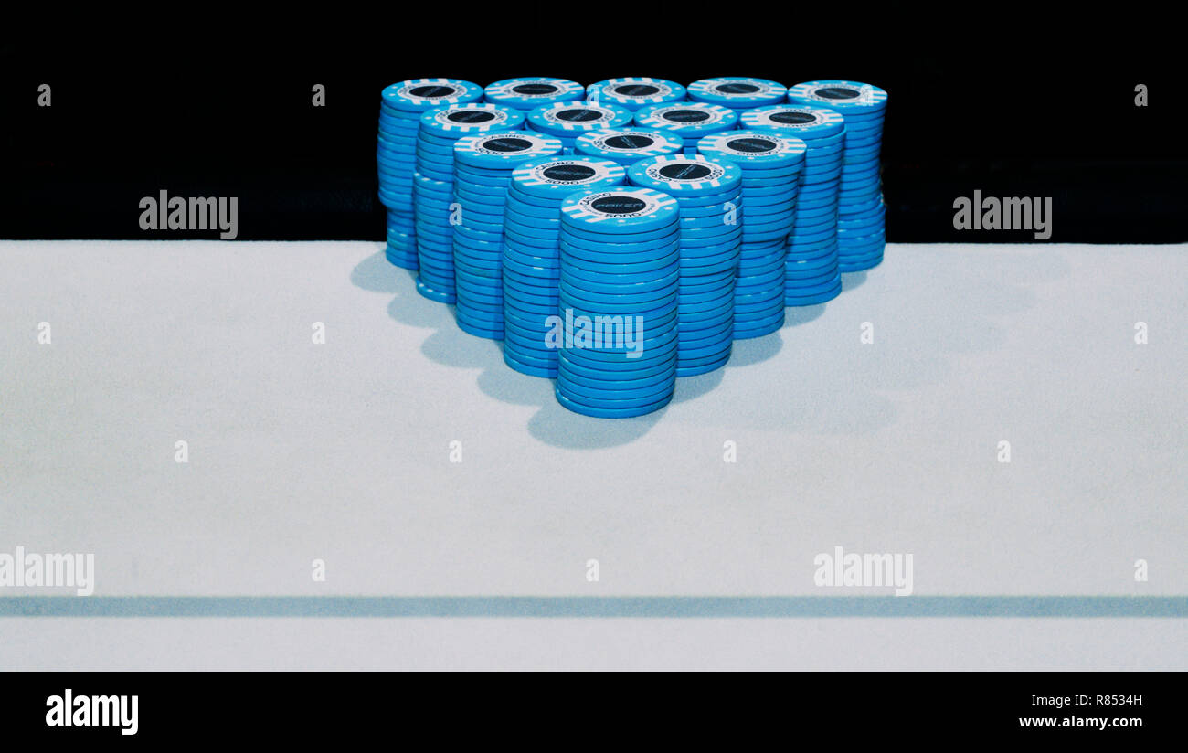 Pyramid of piles of blue poker chips on table with copy space