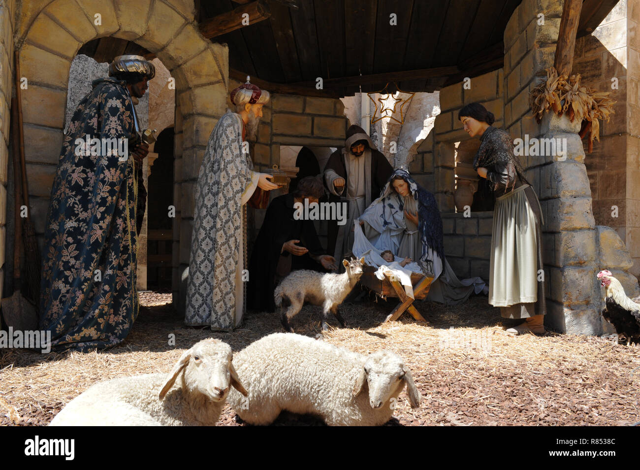 Birth of Jesus in Bethlehem on Christmas Day with three wisemen in full robes bearing gifts for Baby in Manger near Mary and Joseph in sheep stable. Stock Photo