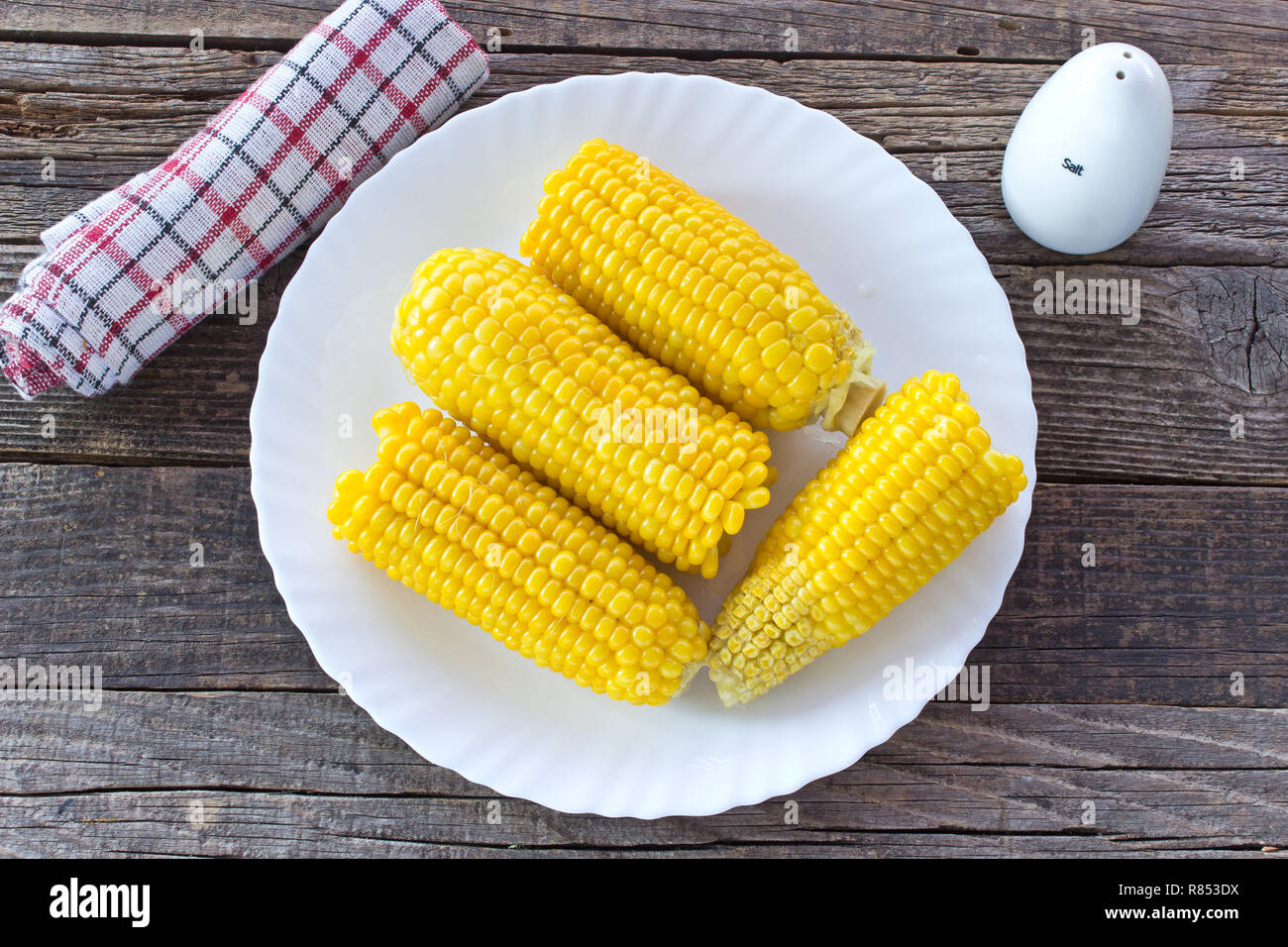 Cooked corn cobs in plate on wooden table Stock Photo