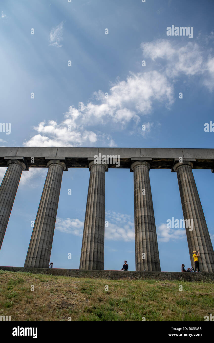 The doric columns of the National Monument of Scotland towers above visitors, Edinburgh, Scotland, UK. Stock Photo