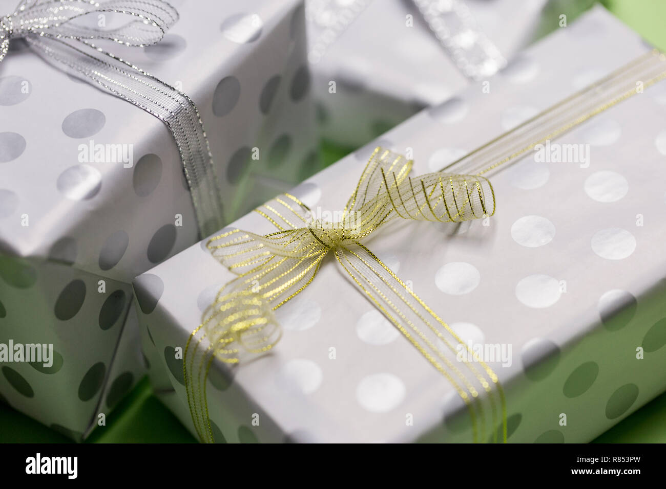 Gift boxes in peas with silver and gold bows at green background, top view, border design with copy space, template for text Stock Photo