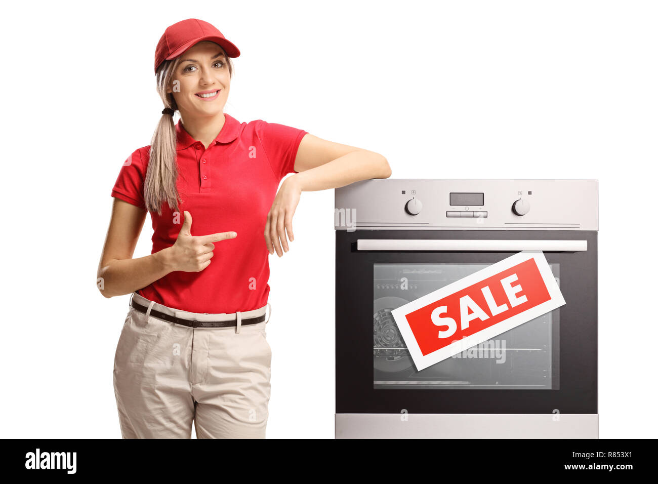 Young saleswoman pointing to an electrcal oven on sale isolated on white background Stock Photo