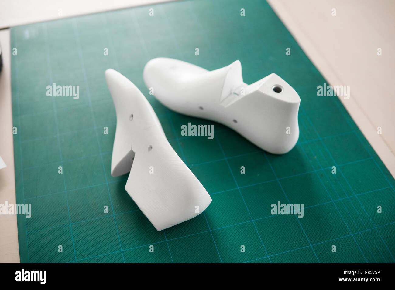 Two White Plastic Last Shoe On Rubber Secondary Cut Cutting Mat