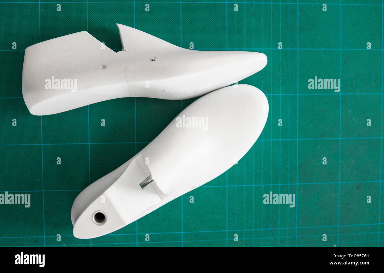 Two White Plastic Last Shoe On Rubber Secondary Cut Cutting Mat
