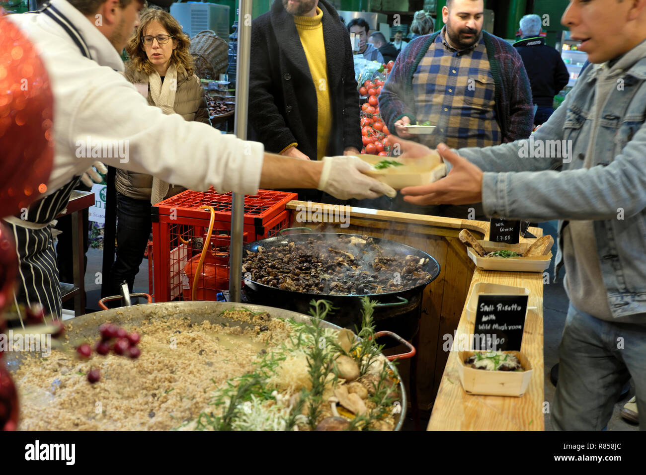 An Italian chef handing a customer a food carton with hot wild mushroom