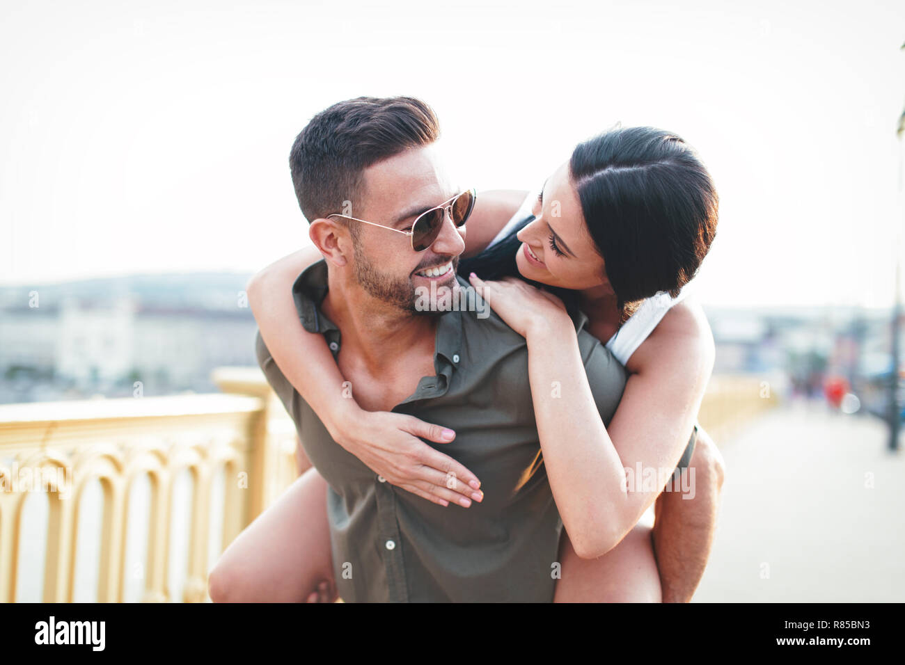 Carefree young caucasian urban couple doing piggyback at outdoors, happiness and joy Stock Photo