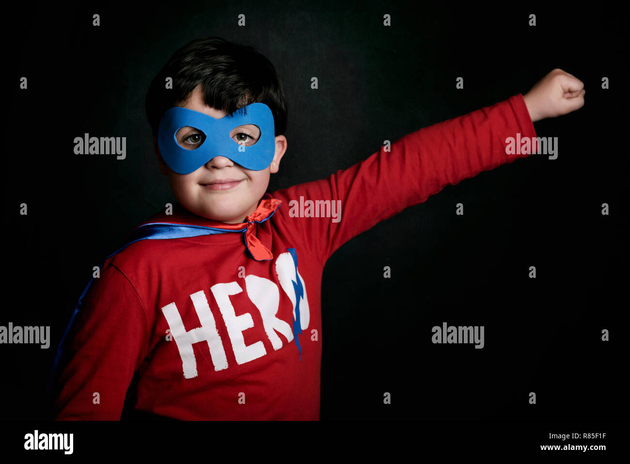 Portrait of boy in superhero costume on black background Stock Photo