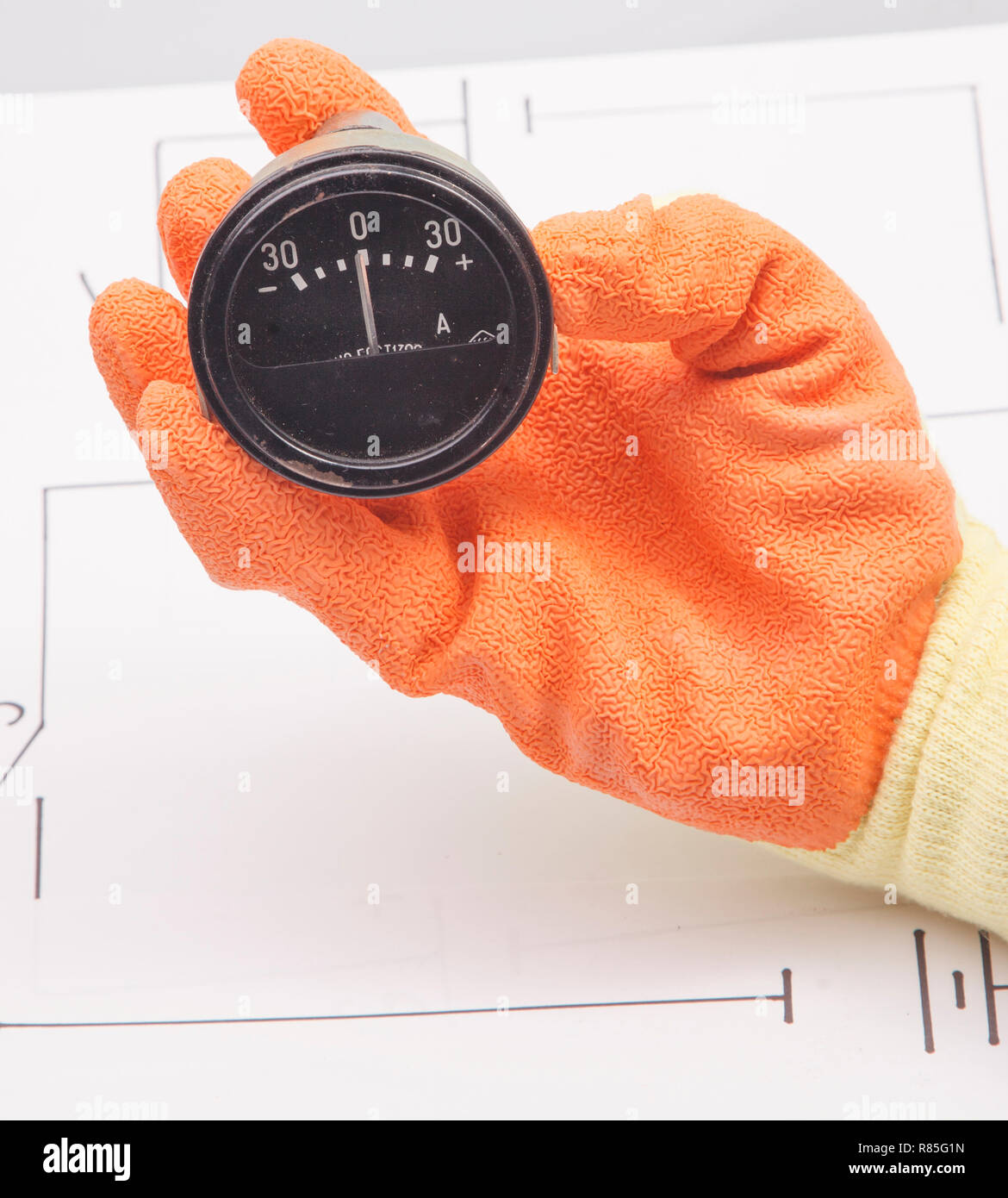 Hand hold ammeter on a background of the electric scheme Stock Photo