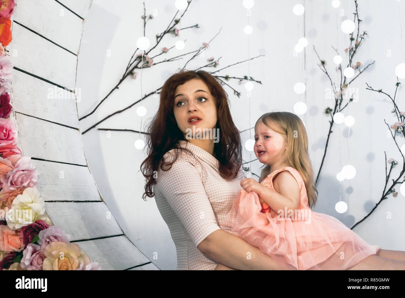 Young woman sitting with crying upset daughter. Tearful baby girl in ...