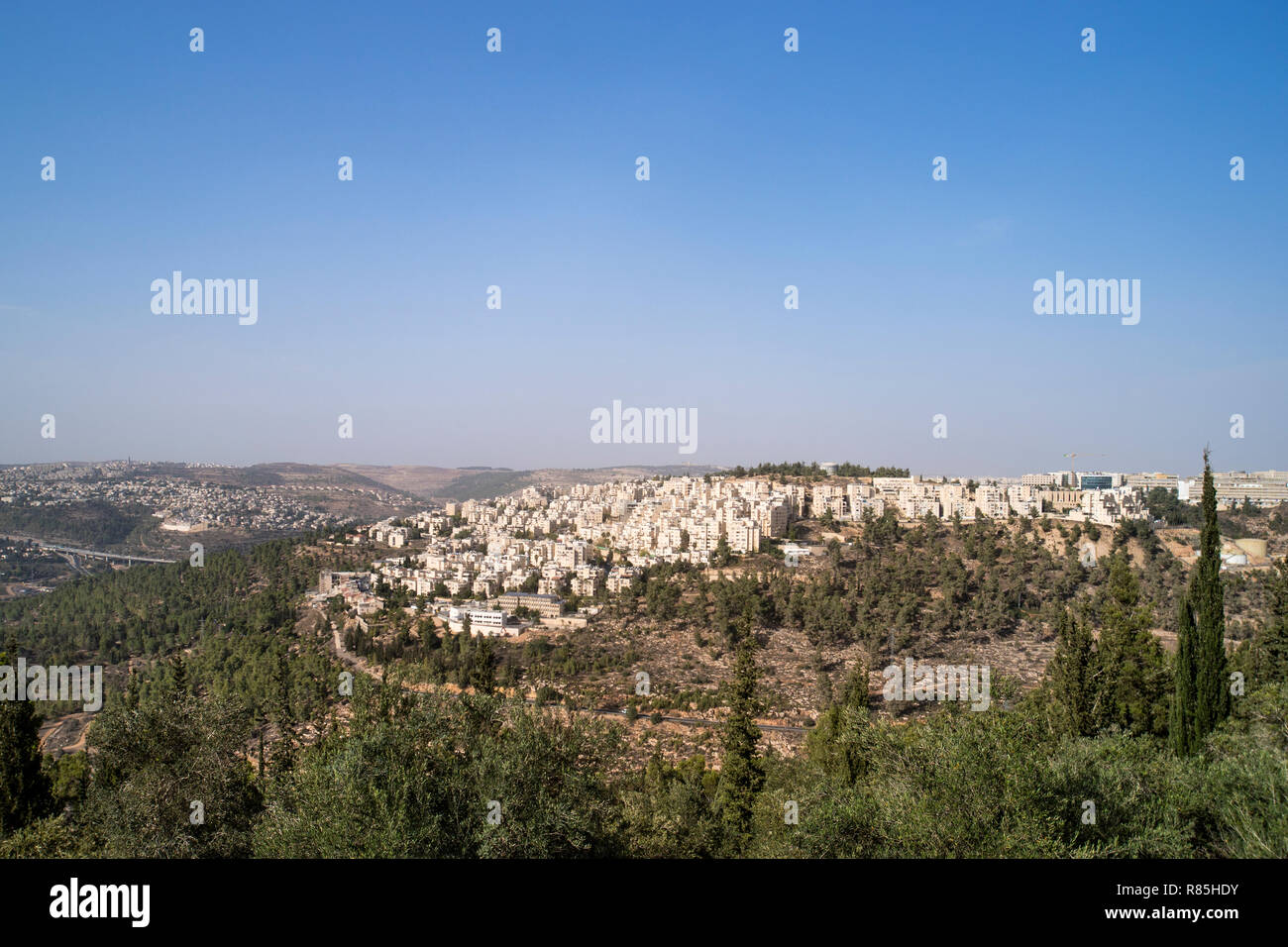 Panoramic aerial view on highway among the hills of Jerusalem, Israel. Modern houses of Jerusalem on a slope on the outskirts of the city among the tr Stock Photo