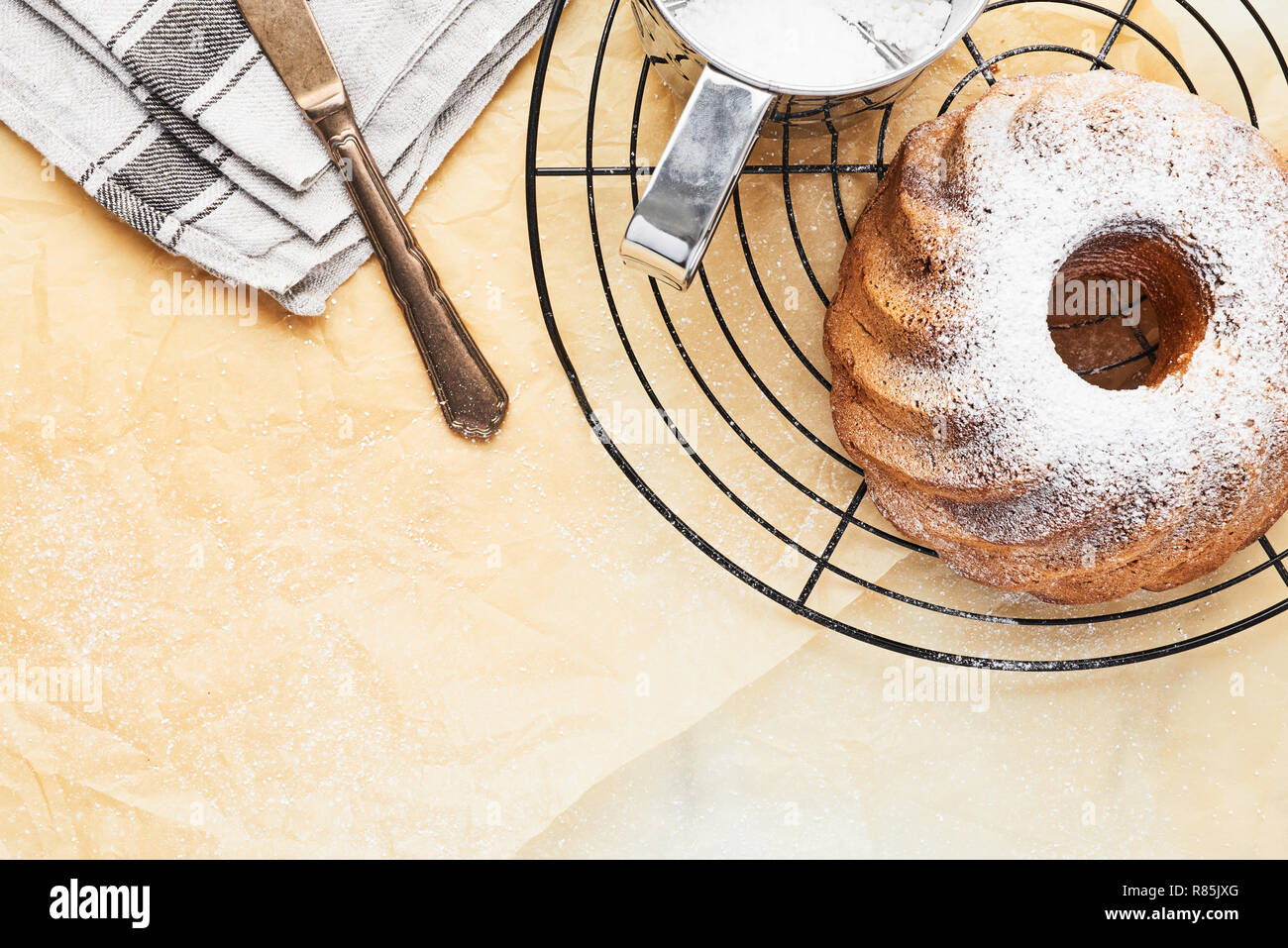 Marble pound cake on french cooling rack with powdered sugar over baking paper. Holiday baking background. Top view with copy space for text. Stock Photo