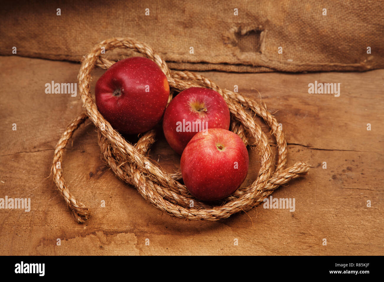 Red apple and green apple in basket with burlap background texture