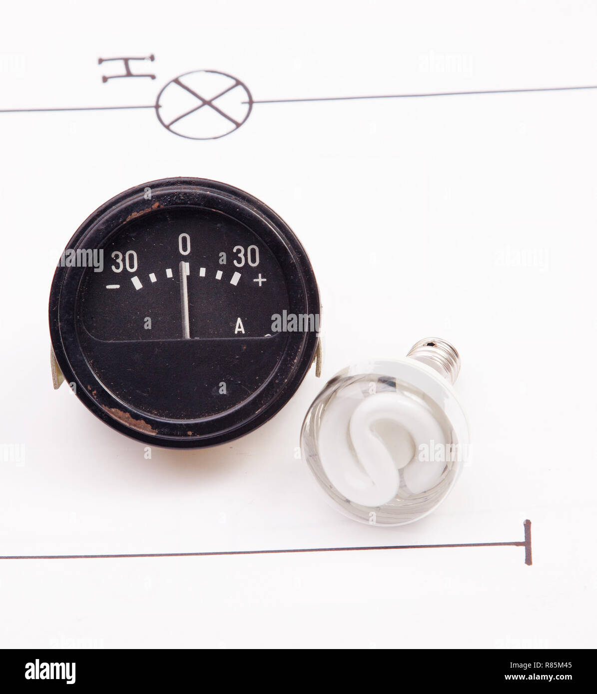 Ammeter and energy saving lamp on a background of the electric scheme Stock Photo