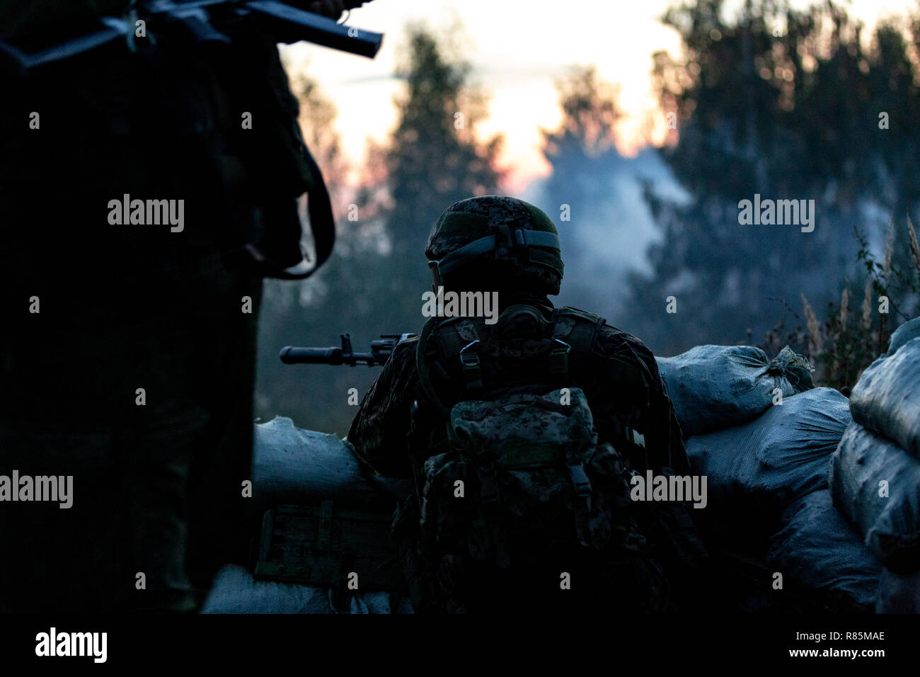 Sniper team armed with large caliber, sniper rifle, shooting enemy targets on range from shelter, sitting in ambush Stock Photo