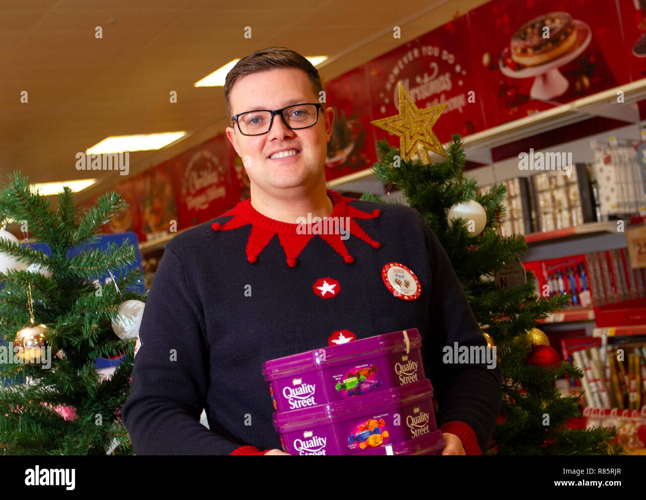 Southport, Merseyside, UK. 13th Dec, 2018. Paul (Manager) displays Christmas spirit at Tesco as employees join in the festive fun. Tesco employees entered into the Christmas festive spirit by supporting Save the Children's Christmas jumper day. Staff agreed to simply stick on a silly sweater and encourage donations to help save children's lives. Friday marks the seventh annual Christmas Jumper Day raising funds for charity on the woollen sartorial event of the year, Credit: MediaWorldImages/AlamyLiveNews. Stock Photo