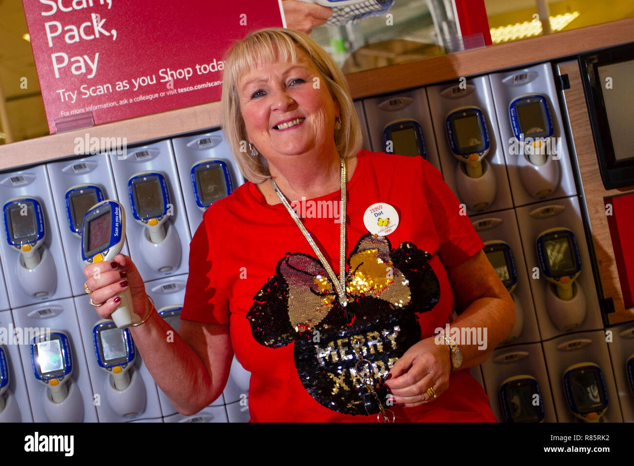 Southport, Merseyside, UK. 13th Dec, 2018. Dorthy Mawdsley (MR) displays Christmas spirit at Tesco as employees join in the festive fun. Tesco employees entered into the Christmas festive spirit by supporting Save the Children's Christmas jumper day. Staff agreed to simply stick on a silly sweater and encourage donations to help save children's lives. Friday marks the seventh annual Christmas Jumper Day raising funds for charity on the woollen sartorial event of the year, Credit: MediaWorldImages/AlamyLiveNews. Stock Photo