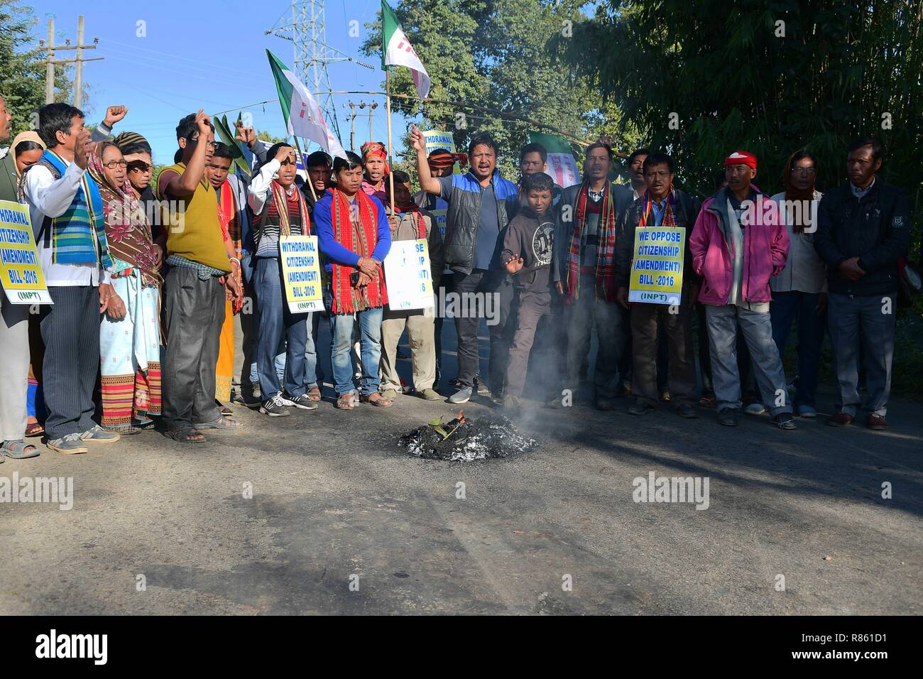 Agartala, Tripura, India. 10th Dec, 2018. Protesters are seen standing before the burning fire while chanting slogans during the protest.INPT (Indigenous Nationalist Party of Twipra) leaders and supporters protest on the National High way in Khamtingbari, 40 km far from Agartala city to demand for the withdrawal of Citizenship Bill that was Introduced in July 19 in Lok Sabha, the Citizenship Amendment Bill 2016 seeks to allow illegal migrants from certain minority communities in Afghanistan, Bangladesh and Pakistan eligible for Indian citizenship. In other words, it amends the Citizenshi Stock Photo