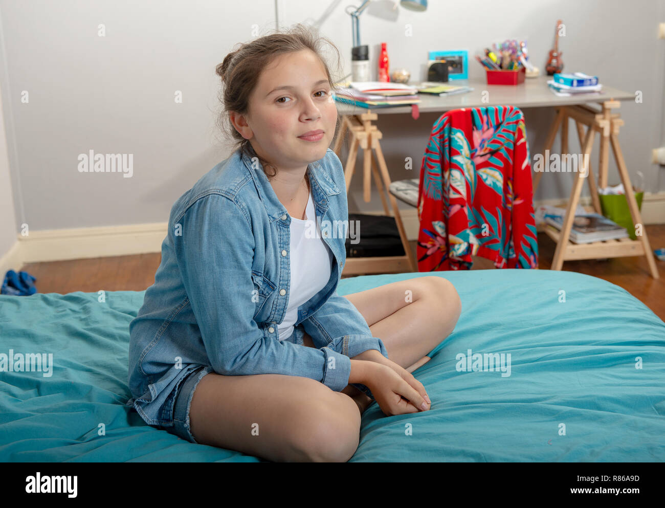 a young teenage girl sitting in cross-legs on the bed Stock Photo - Alamy