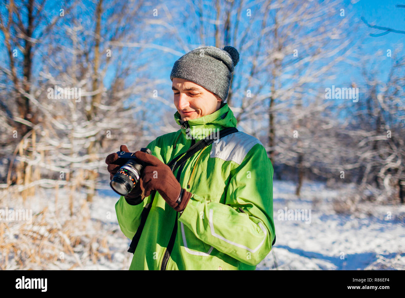 Young photographer checking pictures of winter forest using camera ...
