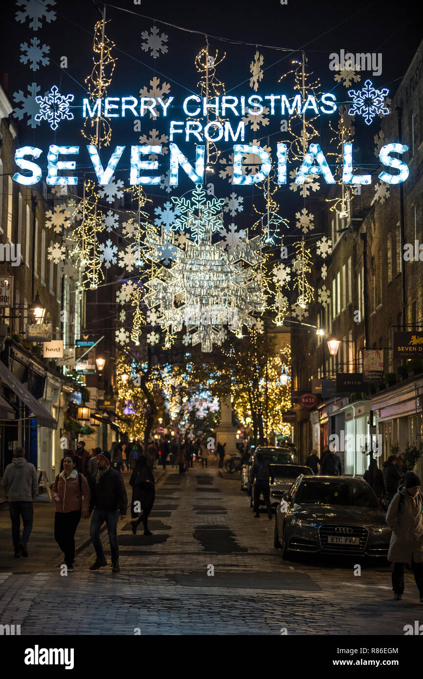 LONDON - NOVEMBER 26, 2018: Merry Christmas message and holiday lights twinkle above a scenic cobblestone street leading to the Seven Dials district. Stock Photo