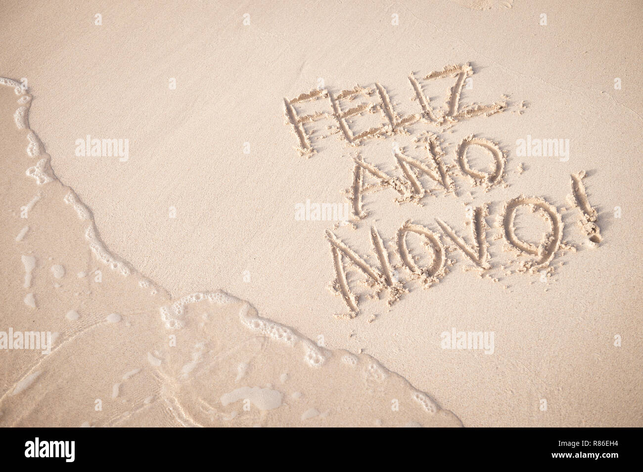 Feliz Ano Novo message (Happy New Year in Portuguese) handwritten on the smooth sand of Copacabana Beach in Rio de Janeiro, Brazil Stock Photo